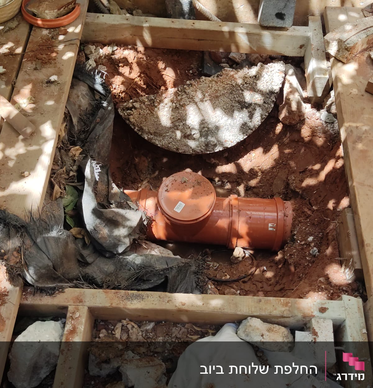 צינור כתום מונח בתוך חפירה באדמה